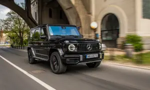 Czarny Mercedes G63 z okrągłymi światłami LED pędzi pod wiaduktem.