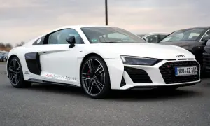 Białe Audi R8 V10 z napisem "Audi Zentrum Rostock" na progu, zaparkowane na zewnątrz.