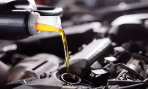 Wlewam olej do silnika Toyoty Yaris 1.0. Złoty płyn spływa z butelki do otworu.