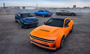 Pomarańczowy i niebieski Dodge Charger, szary Dodge Challenger i niebieski Dodge Charger stoją nad wodą z mostem w tle.
