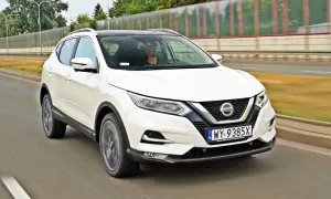 Biały Nissan Qashqai jedzie po drodze. Sprawdź aktualną nissan qashqai cena i oferty.