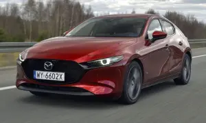 Czerwona Mazda 3 2.0 150KM w ruchu. Kierowca za kierownicą, dynamiczna jazda po drodze.