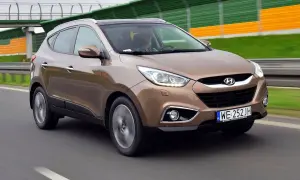 Brązowy Hyundai i35 na drodze, z zielono-żółtymi barierami dźwiękochłonnymi w tle.