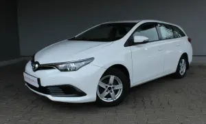 Biała Toyota Auris II 1.6 132 KM, kombi, na chodniku. Wiele osób szuka o niej pozytywnych opinii.