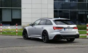 Srebrne Audi RS6 Avant z czarnymi felgami stoi na parkingu przed nowoczesnym budynkiem.