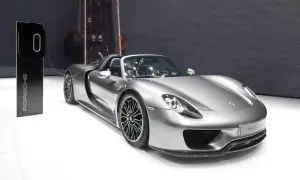 Srebrny Porsche 918 Spyder z zielonymi akcentami na felgach, gotowy do ładowania przy stacji Porsche.