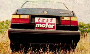 Tylna część Volkswagena Vento z tabliczką "test motor" na tle trawy i krzewów.