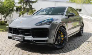 Szary Porsche Cayenne Turbo GT z żółtymi zaciskami hamulcowymi stoi na brukowanej nawierzchni.