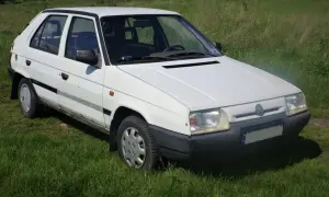Biały Skoda Favorit stoi na trawie.