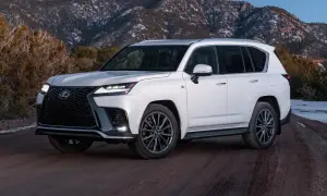 Biały Lexus LX 600 na drodze gruntowej, z ośnieżonymi górami w tle.