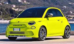 Jaskrawożółty Abarth 500 EV z czarnym dachem stoi na tle wzgórz i morza.