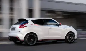 Biały Nissan Juke 1.5 dCi w wersji Nismo, z czerwonymi akcentami, pędzi ulicą. Jego sportowy wygląd budzi pozytywne opinie.