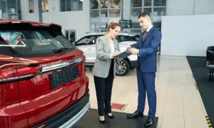 Kobieta podpisuje dokumenty przy nowej, czerwonej Toyocie. To jej pierwszy przegląd gwarancyjny.