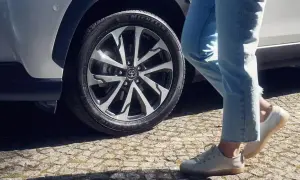 Osoba w jeansach i białych butach zbliża się do Toyoty Corolli. Dowiedz się, jak zresetować czujnik ciśnienia w oponach.