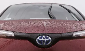 Czerwona Toyota z kroplami deszczu na masce i logo. Czy toyota ma ocynkowane blachy? Ta z pewnością jest dobrze zabezpieczona.