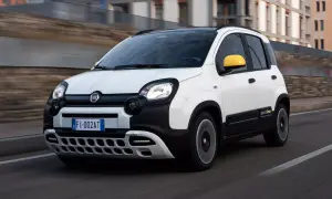Biały Fiat Pandina z żółtymi lusterkami pędzi po drodze.