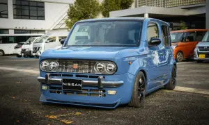 Niebieski Nissan Cube z chromowanymi zderzakami i grillem, obniżonym zawieszeniem i czarnymi felgami.