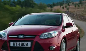 Czerwony Ford Focus 2011 na krętej drodze wśród zieleni.