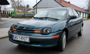 Zielony Dodge Neon z tablicą rejestracyjną WN 1490T stoi na mokrej drodze.