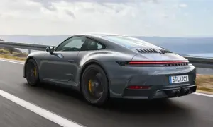 Szary Porsche 911 GTS pędzi po krętej drodze z widokiem na morze.