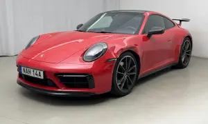 Czerwone Porsche 992 z widocznym uszkodzeniem na błotniku, stojące na szarym podłożu.