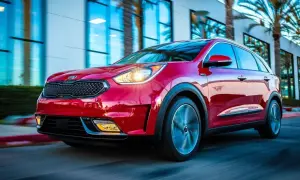 Czerwony Kia Niro w ruchu. Choć auto wygląda dynamicznie, warto pamiętać o jego potencjalnych wadach, np. ograniczonym zasięgu w wersji hybrydowej.