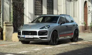 Srebrny Porsche Cayenne GTS z czerwonymi akcentami na progach, zaparkowany na brukowanej ulicy przed zabytkową kamienicą.