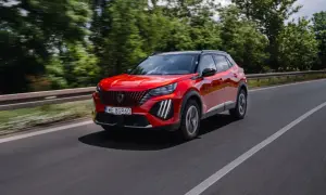 Czerwony Peugeot 2008 GT pędzi po drodze, otoczony zielenią drzew.