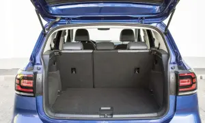 Błękitny Volkswagen T-Cross z otwartym bagażnikiem. Widać tylne siedzenia i przestronną przestrzeń bagażową, idealną na wakacyjne wyjazdy.