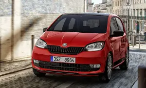 Czerwony Skoda Citigo z czarnym dachem pędzi ulicą miasta.