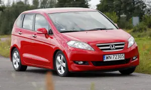 Czerwona Honda FR-V na drodze, z widocznym logo i tablicą rejestracyjną.