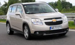 Złoty Chevrolet Orlando na drodze. Kierowca w środku. Wiele osób szuka chevrolet orlando opinie, ten samochód może być dobrym wyborem.