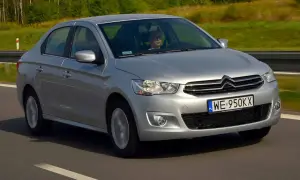 Srebrny Citroen C Elysee jedzie po drodze, za kierownicą siedzi mężczyzna.
