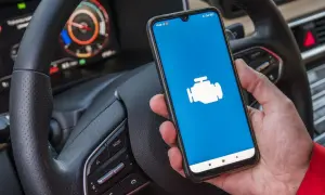 Ręka trzyma smartfon z ikoną silnika, gotowy do diagnostyki Toyoty. Jaki program do Toyoty z ELM327?