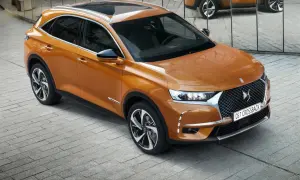 Pomarańczowy Citroën DS7 Crossback lśni na tle lustrzanej ściany. Elegancki SUV prezentuje swoje nowoczesne linie.
