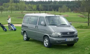 Szary VW T4 2.5 TDI 102KM na polu golfowym. Kobieta z kijami golfowymi obok.