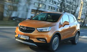 Pomarańczowy Opel Mokka 2015 pędzi ulicą, odbijając światła miasta w swojej lśniącej karoserii.