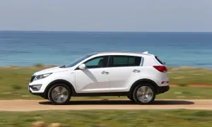 Biały Kia Sportage 2013 jedzie przy błękitnym morzu.