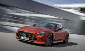 Pomarańczowy Mercedes-AMG GT 63 S pędzi obok nowoczesnej architektury.