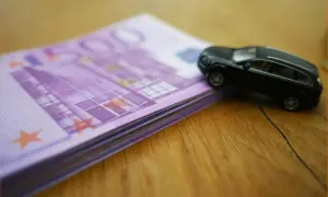 Czarny model samochodu na stosie banknotów 500 euro. Wartość rynkowa samochodu, tabela, urząd skarbowy - wszystko w jednym kadrze.