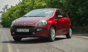 Czerwony Fiat Grande Punto na tle zieleni.