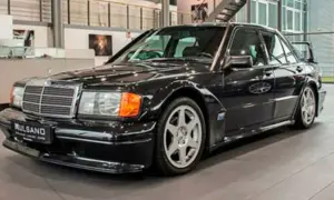 Czarny Mercedes 190 Evo z charakterystycznym spojlerem i felgami, stojący w salonie samochodowym.