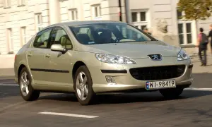 Złoty Peugeot 407 2.0 HDI jedzie ulicą.