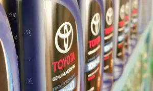 Rząd butelek oryginalnego oleju Toyota. Kto produkuje? Toyota, znana marka samochodów, produkuje również wysokiej jakości oleje silnikowe.