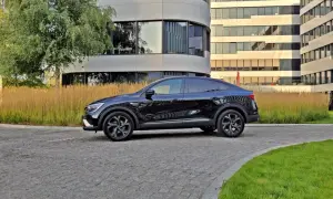 Elegancki, czarny Renault Arkana na tle nowoczesnych budynków biurowych.