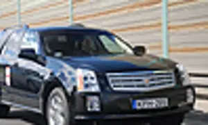 Czarny Cadillac SRX z przyciemnianymi szybami i chromowanymi detalami jedzie po drodze.