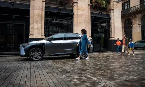 Rodzina idzie obok ładowanego elektrycznego SUV-a Toyoty. EV mode Toyota co to? To przyszłość motoryzacji.