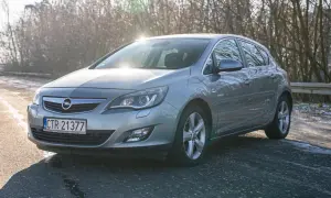 Szary Opel Astra J 1.7 CDTI na tle drzew w zimowym słońcu.