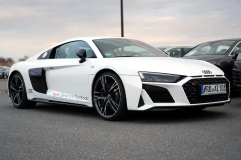 Białe Audi R8 V10 z napisem "Audi Zentrum Rostock" na progu, zaparkowane na zewnątrz.
