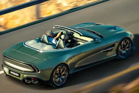 Zielony Aston Martin Vanquish bez dachu pędzi po pustej drodze, kierowca cieszy się wolnością.